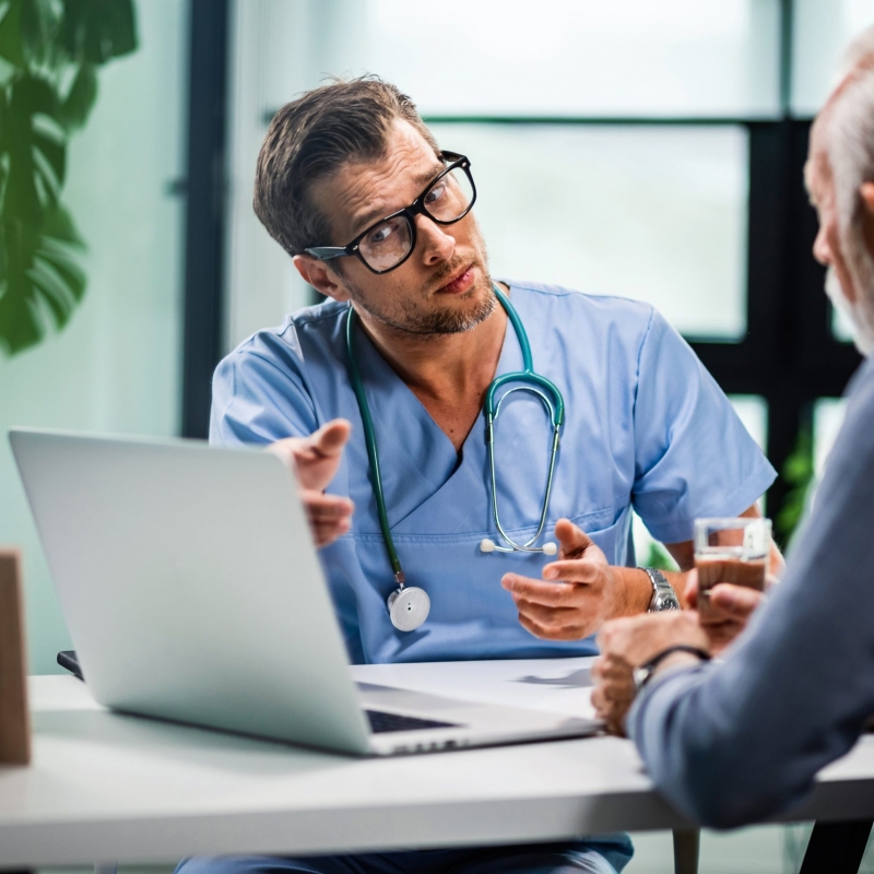 Concerned doctor explaining medical test results on laptop to his patient.